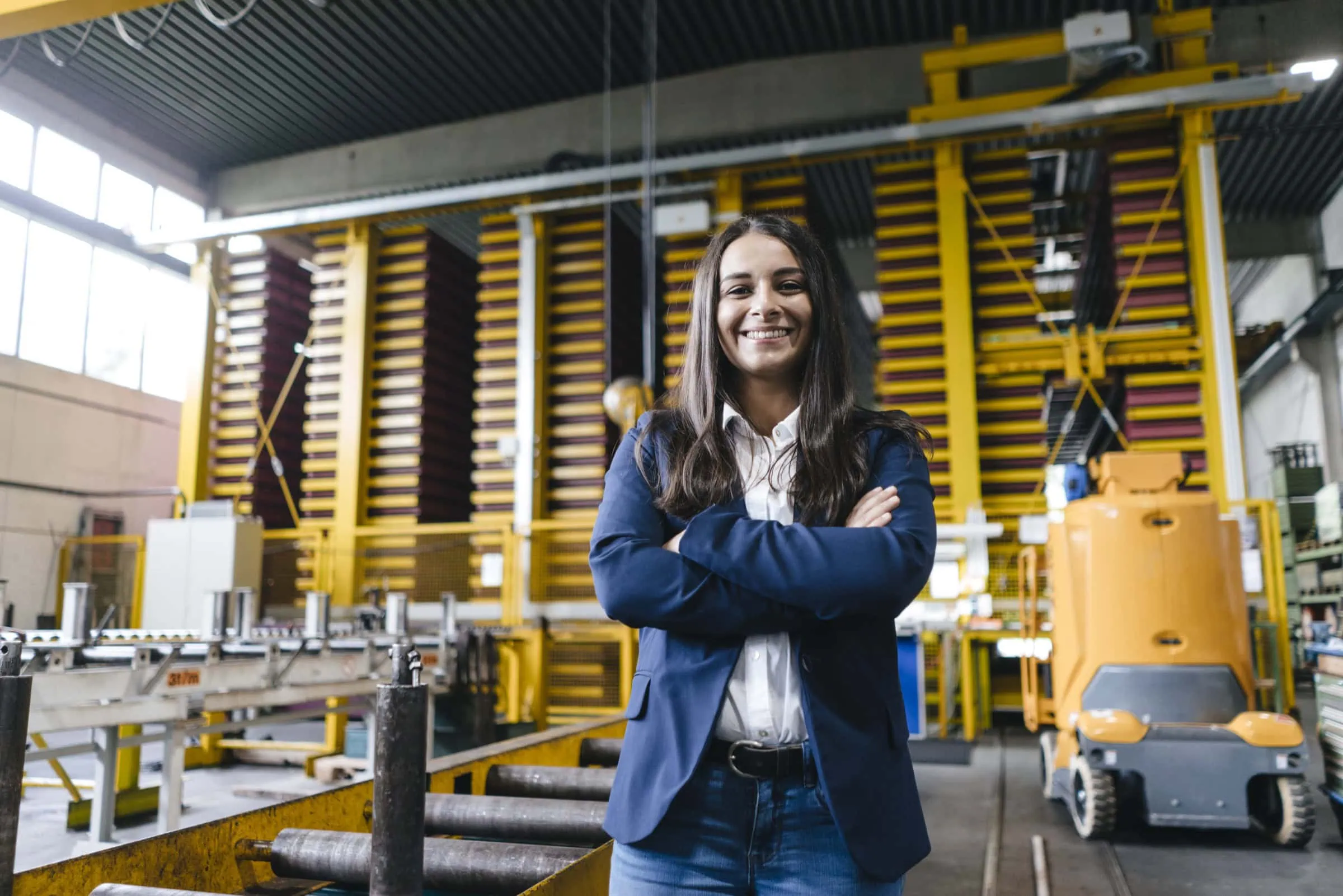 confident woman standing in logistics center, with arms crossed